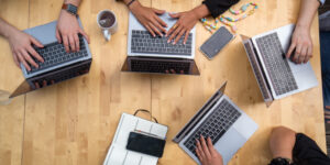 Zwei Menschen sitzen an Laptops und schreiben.